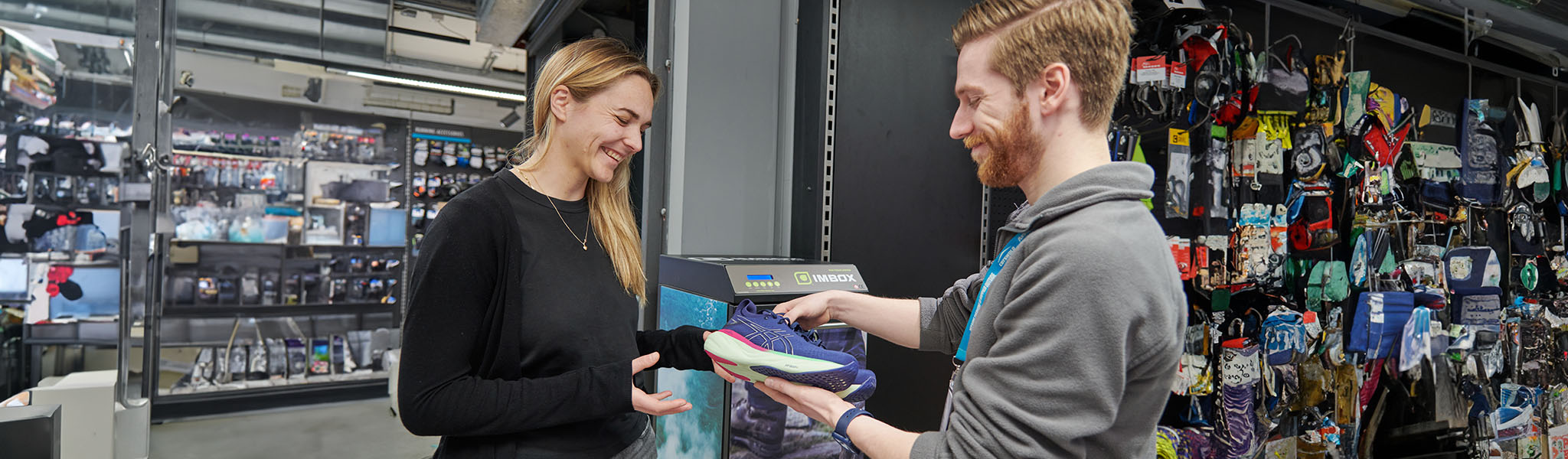 Footwear protection. A smiling shop assistant is giving back a smiling customer her pair of traines after footwear protection treatment. 