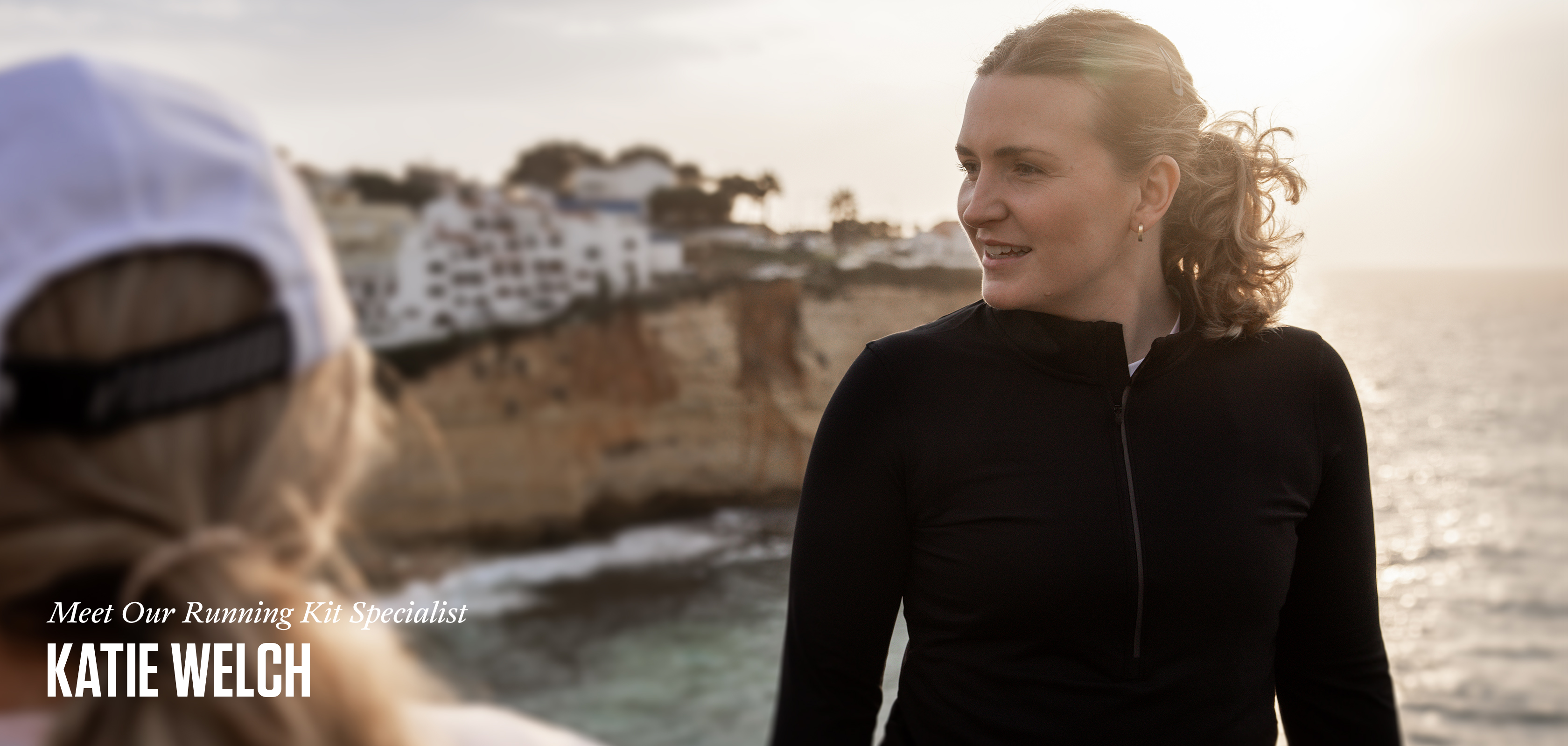 A woman with blonde hair and wearing a black hoody looking down at the ground