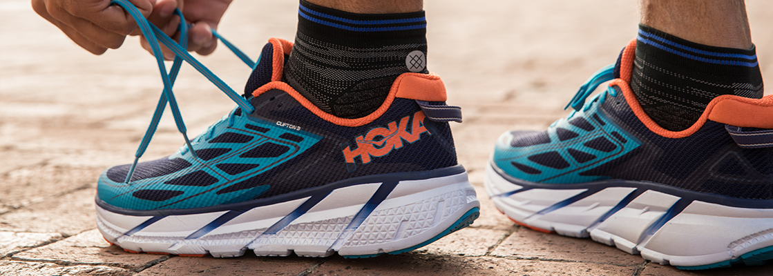 A person tying up their Hoka shoes 