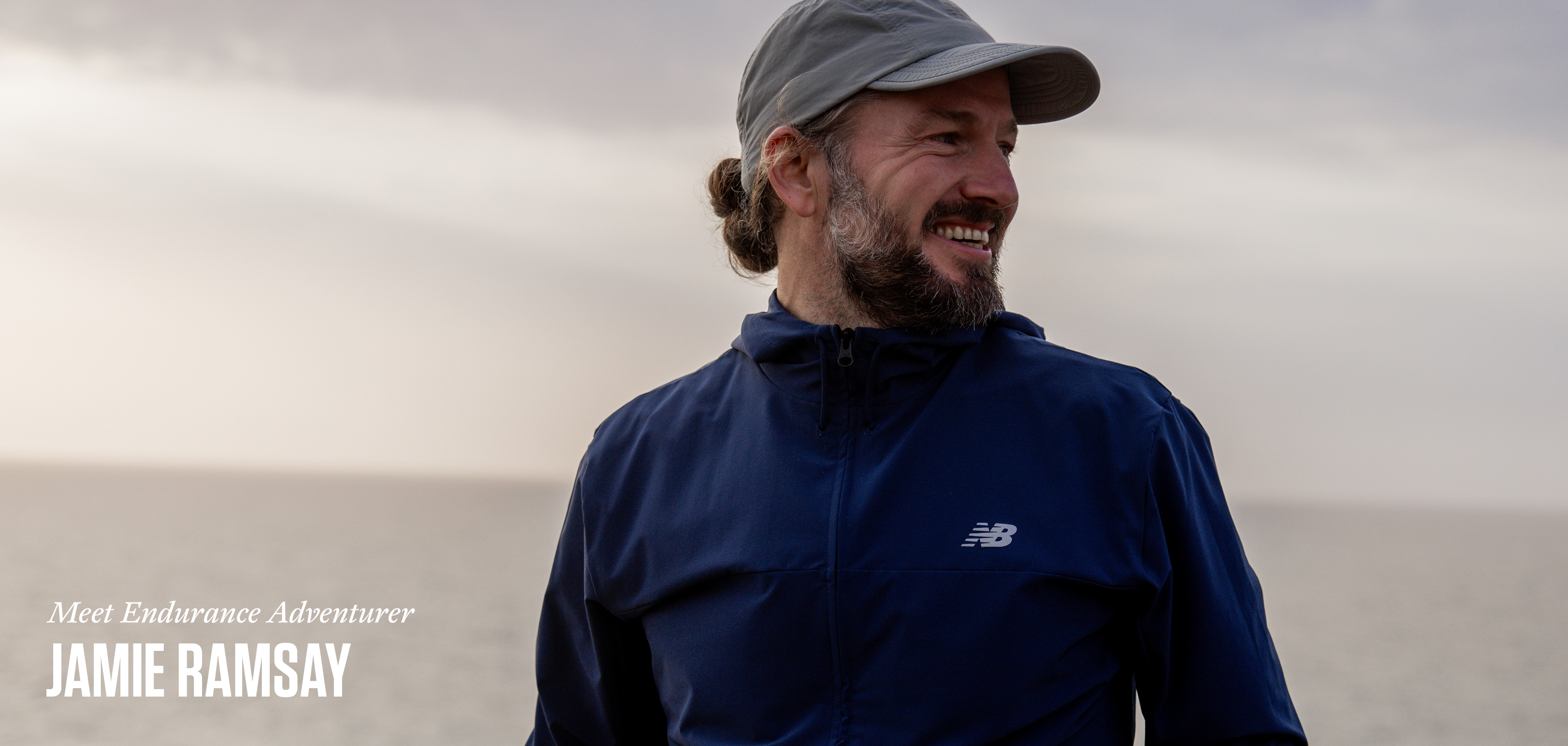 A bearded man wearing a baseball cap looking into the distance 