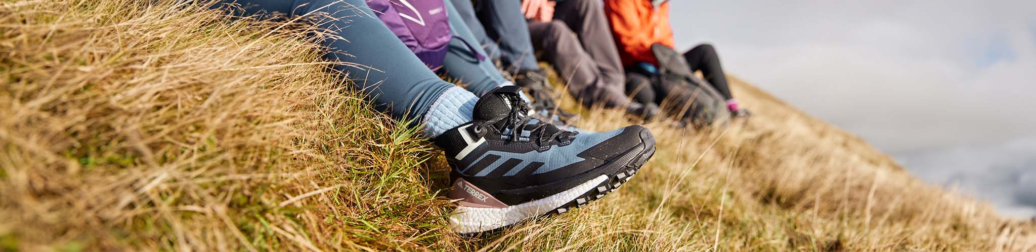 Shop trail shoes. People sat on a hill wearing trail shoes. 