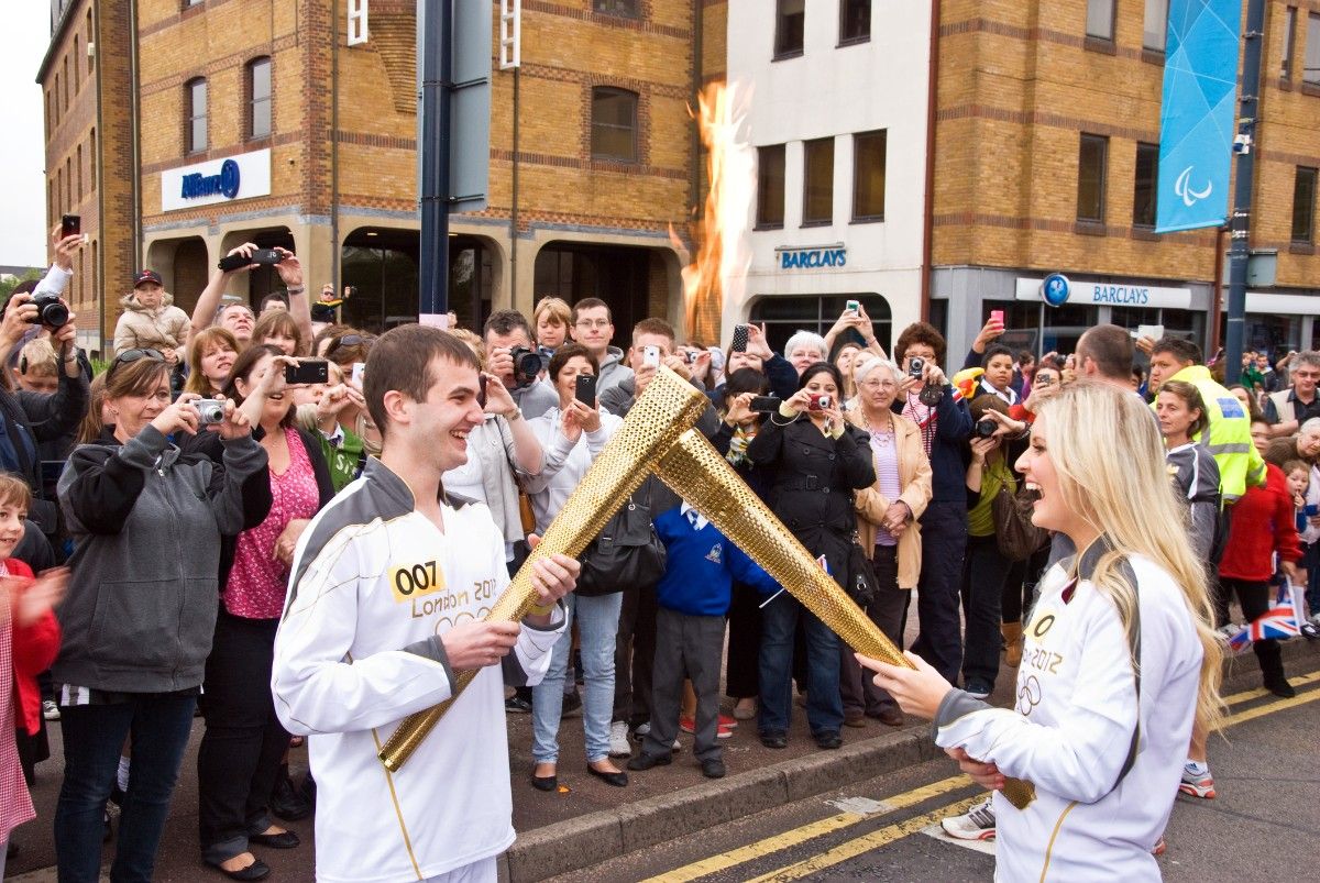 Two people passing the Olympic flame