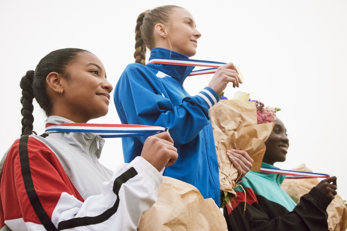 Three women with medals on a podium