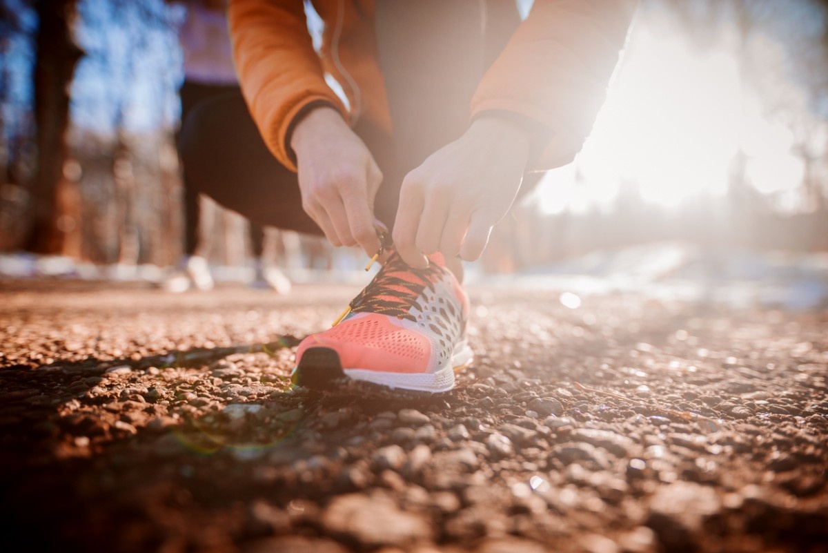 A person tying up their running shoe laces in the park