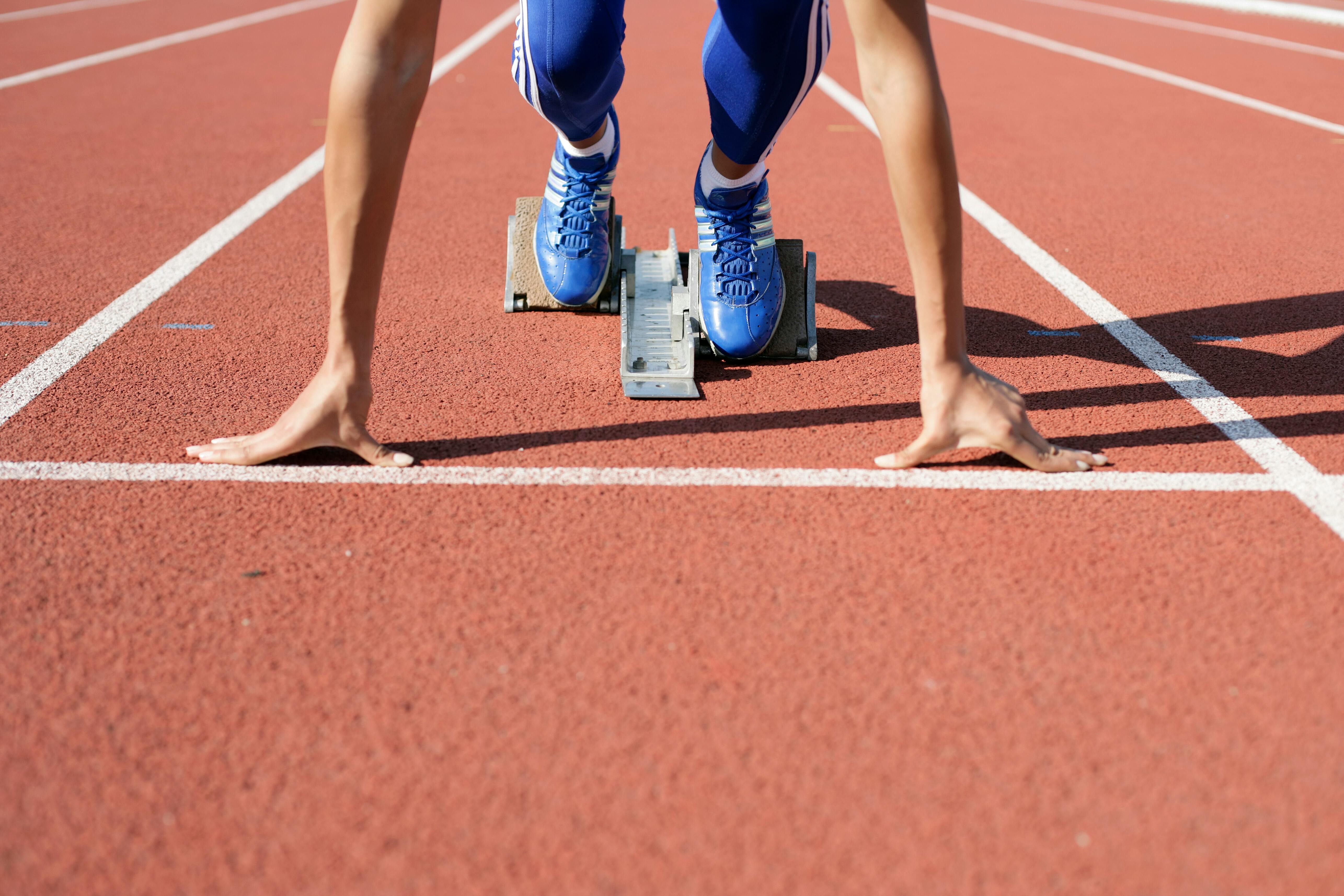 A person getting ready to run on a running track in their Adidas Running Spikes