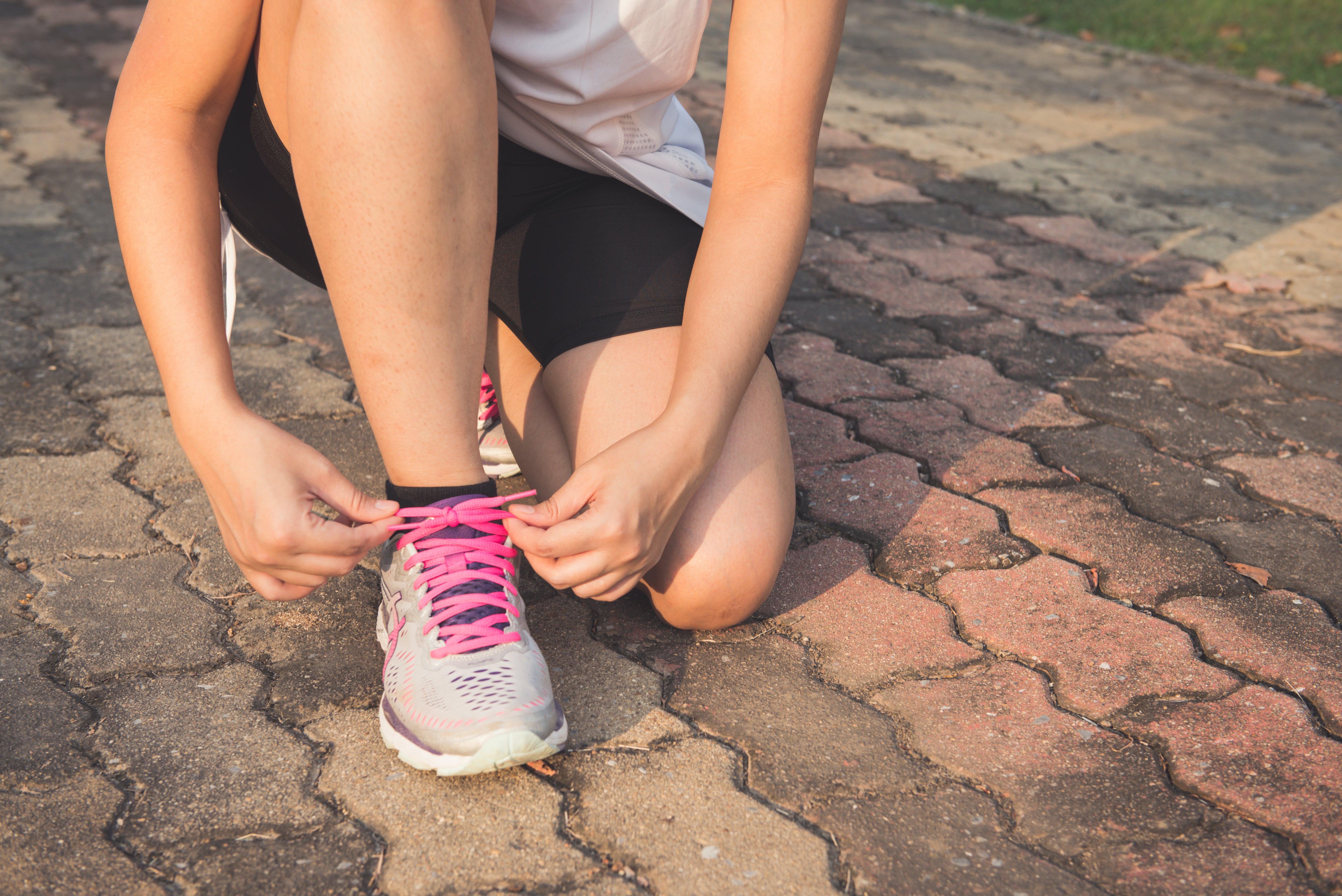 An image of a woman tying up the laces of her running shoes