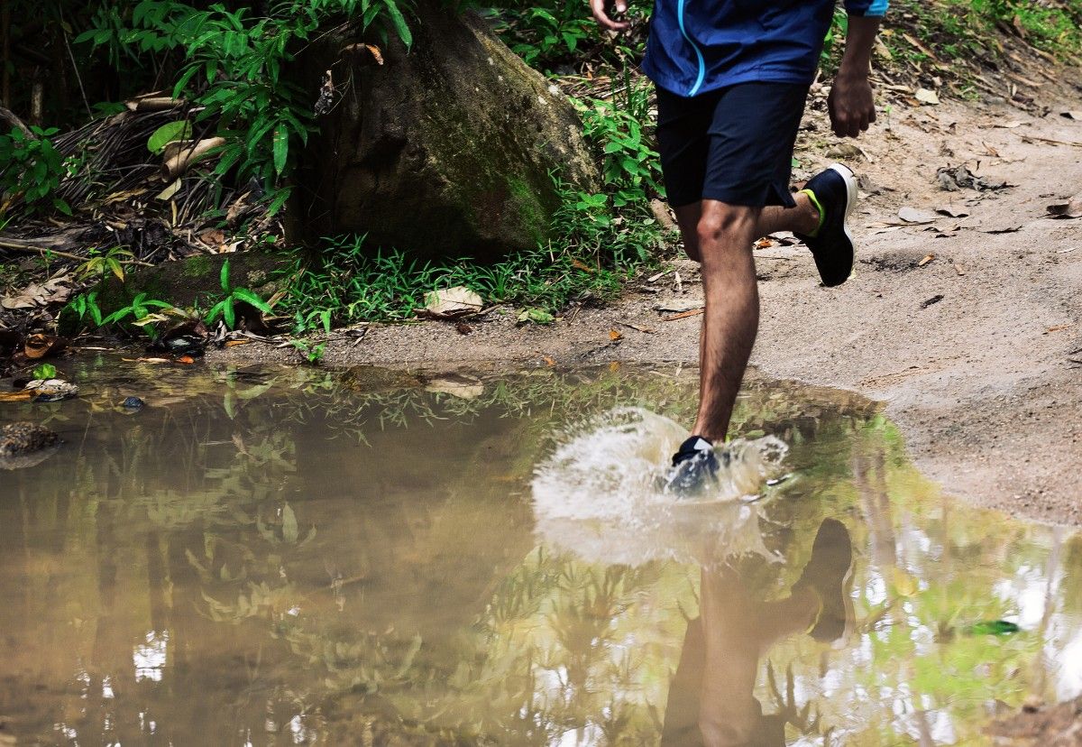 A trail runner going through a puddle 