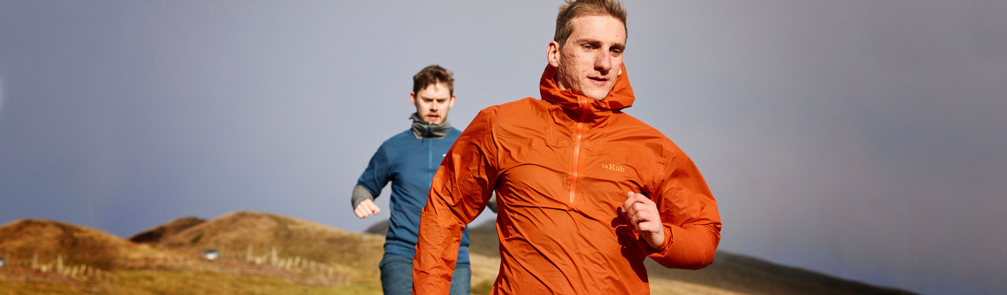 Two men are running in the fields, wearing running kits