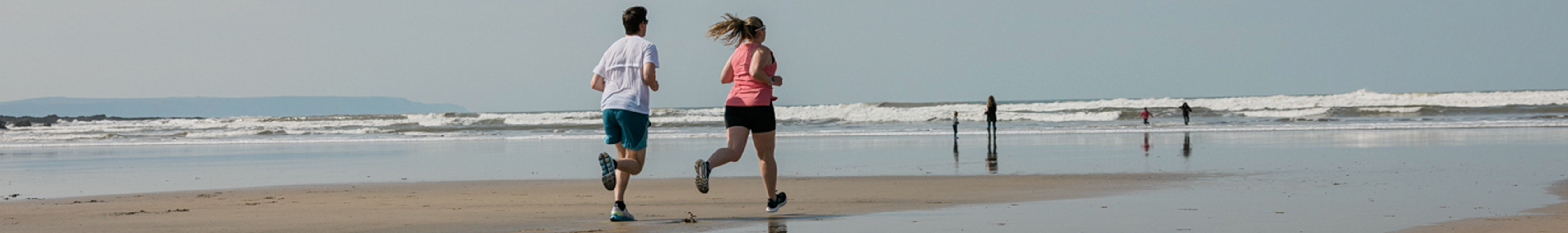 Summer running gear. A woman and man running on a beach