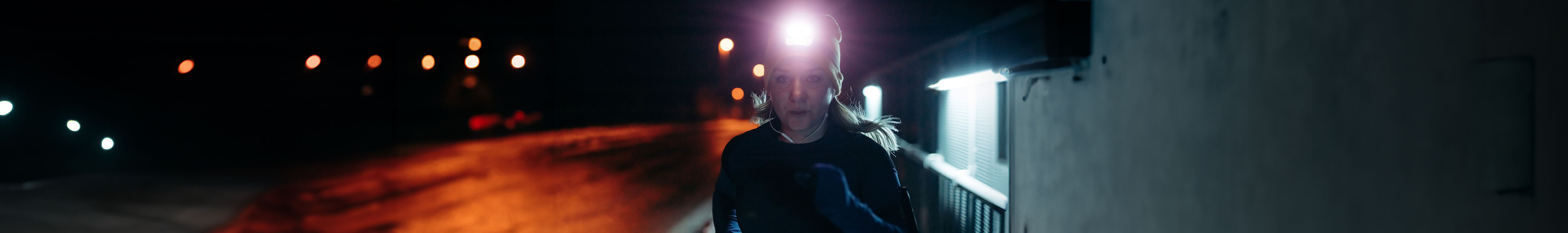 Shop running lights and head torches. A woman wearing head torch running in the dark