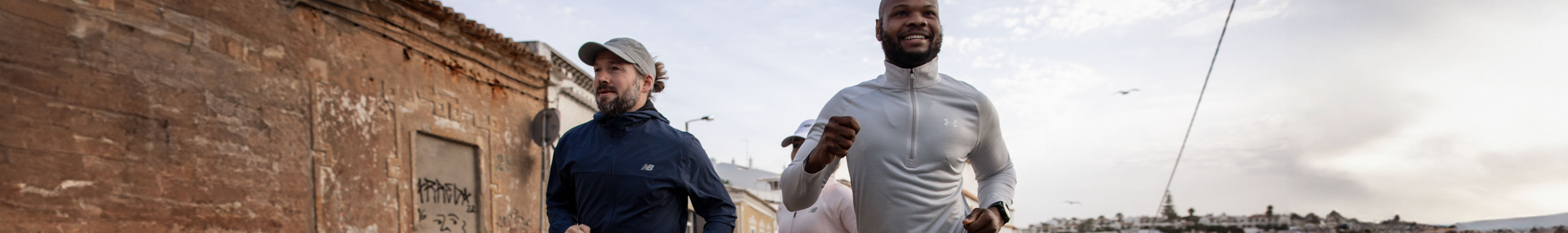 Shop men's clothing. Two men in running clothes running in an urban street