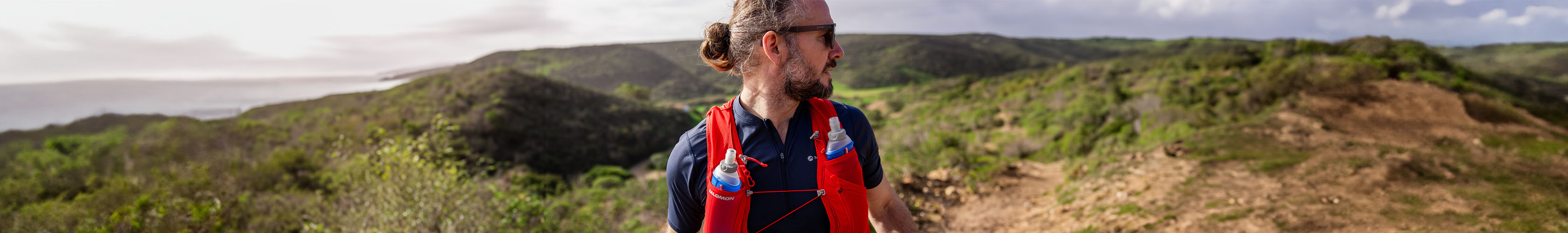 Shop backpacks. A man in a t-shirt, wearing a red backpack