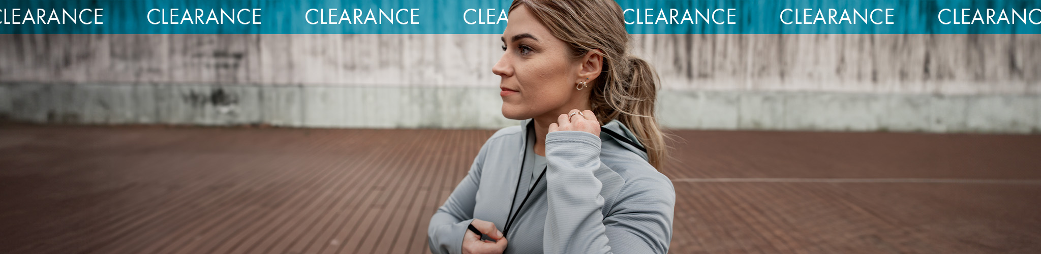 Shop Clothing clearance. A woman wearing grey running jacket and T-shirt