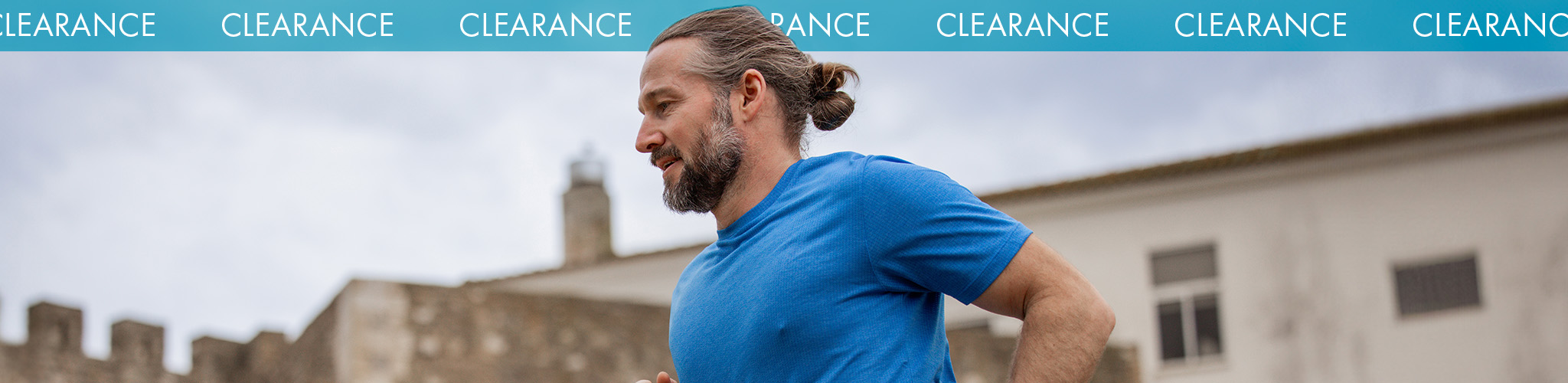 Shop Men's clearance. A man in a blue T-shirt running on the street