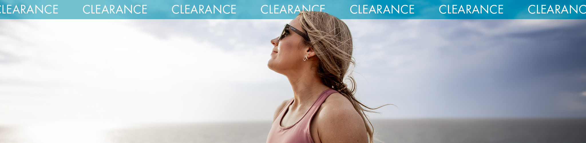 Shop Women's clearance. A woman in running clothes and sunglasses standing outside