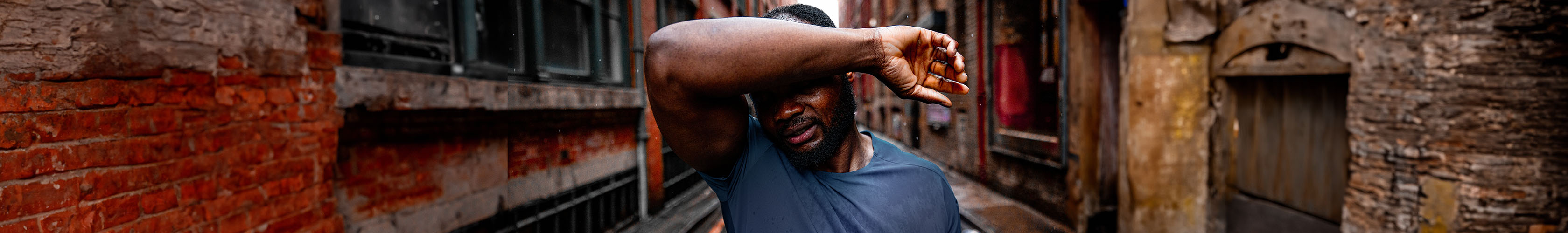 Shop men's new season. A man in a blue t-shirt standing on a street