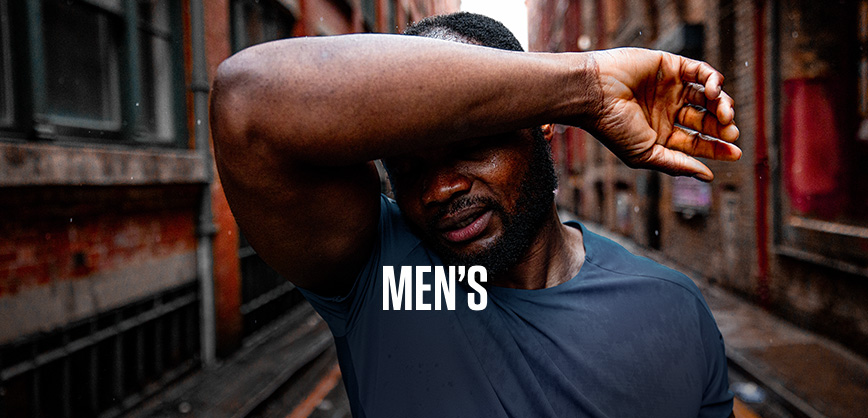 Shop men's collection. A man in a blue t-shirt standing on a street