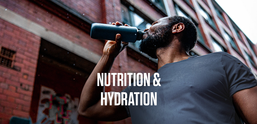 Shop Nutrition & hydration. A woman wearing running backpack is drinking from a water bottle