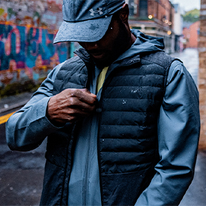 Shop Jackets & gilets. A man in zipping a jacket under a blue gilet