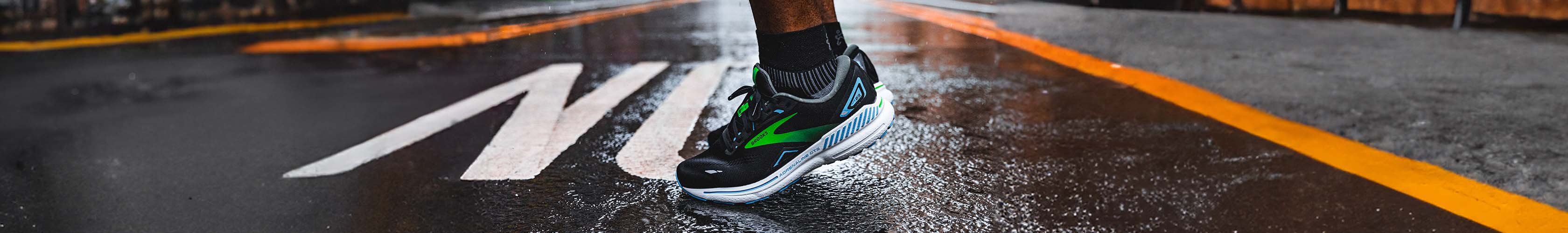 Shop road running shoes. A runner in pair of Brooks shoes preparing for a run on a pavement