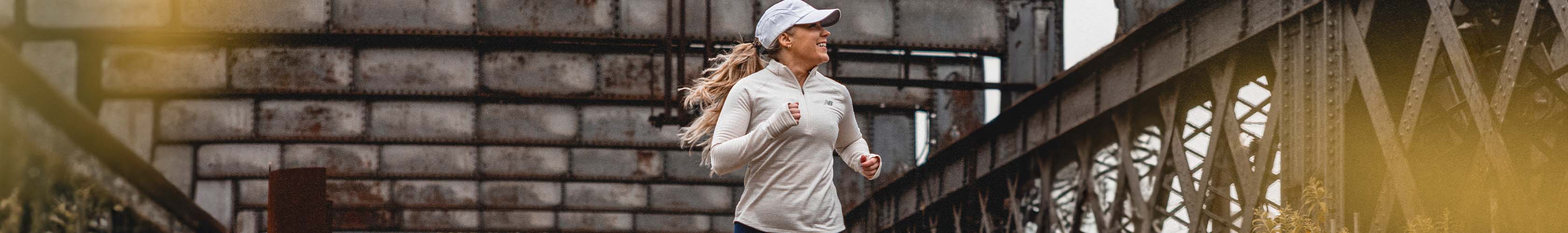 Shop new season running tops. Woman running in a beige long sleeve top and baseball cap