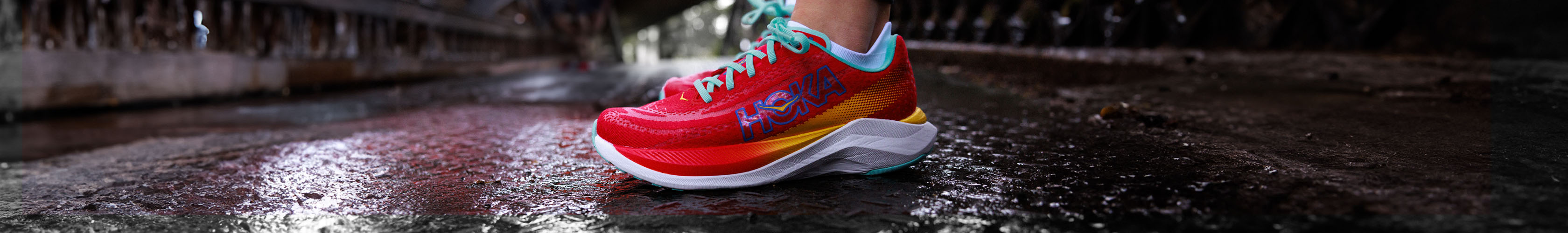 Shop Race & lightweight running shoes. A person wearing red Hoka trainers standing on a pavement