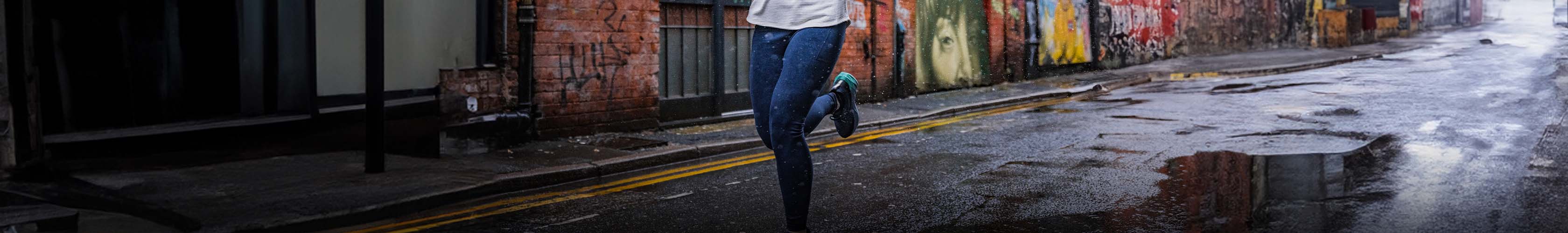 Shop running tights & leggings. Woman in blue leggings running on a road