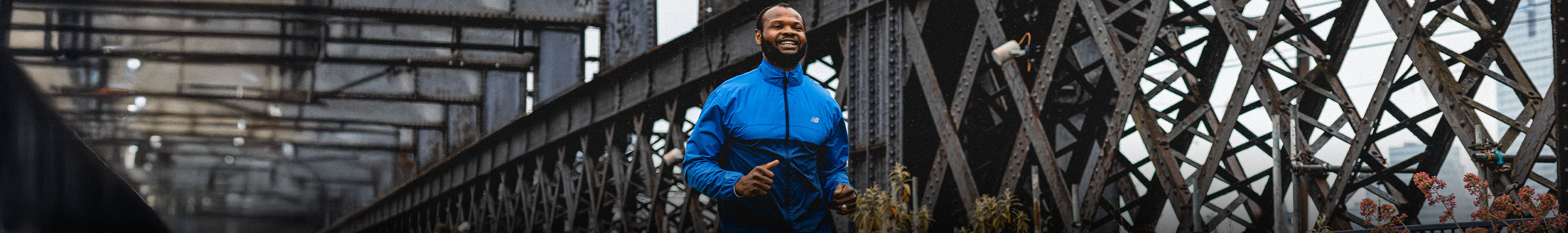 Shop men's new season. A man in a blue jacket running on a street