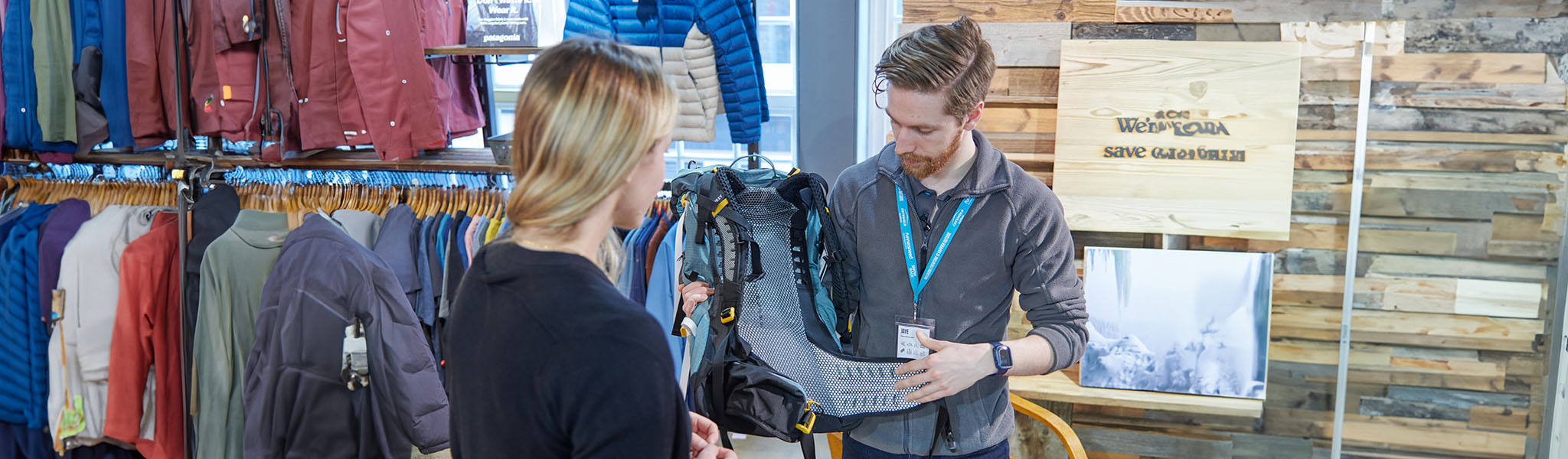 Appointments.  A shop assistant is showing a customer a rucksack